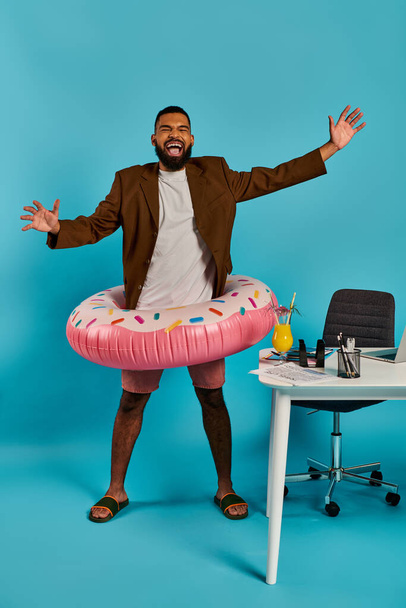 Ein scharf gekleideter Mann im Anzug hält spielerisch einen großen aufblasbaren Donut in den Händen, der einen skurrilen und unerwarteten Anblick bietet. - Foto, Bild