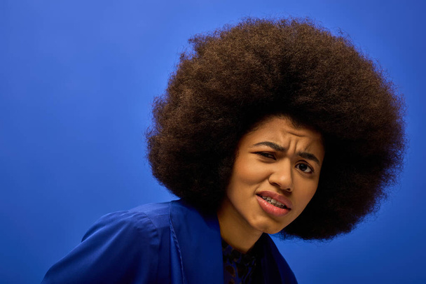 Hareketli bir arka planda etkileyici bir afro saçı olan şık bir Afro-Amerikan kadının yakın çekimi.. - Fotoğraf, Görsel