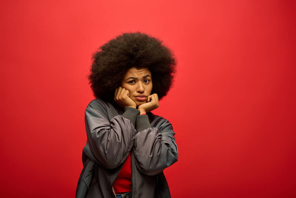 Stylish African American woman in trendy attire posing in front of a vibrant red backdrop. - Photo, Image