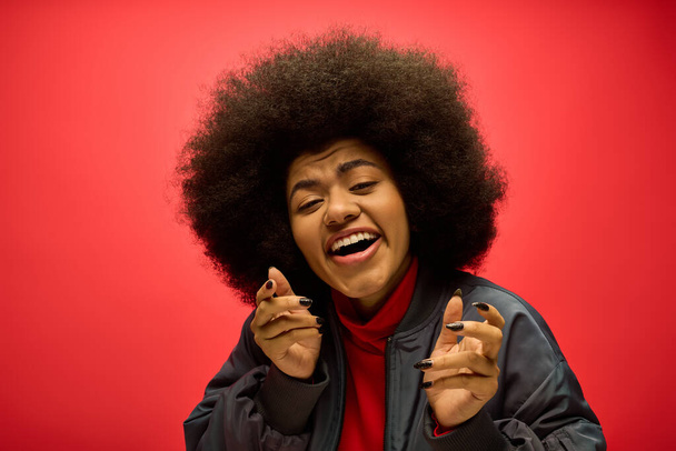 Una mujer con un voluminoso peinado afro está contorsionando humorísticamente su cara. - Foto, imagen