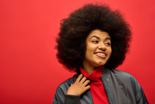 Stylish African American woman with curly hairdo wearing red shirt poses against vibrant backdrop. - Photo, Image