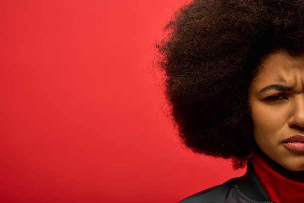 Stijlvolle Afro-Amerikaanse vrouw met een opvallende afro kapsel poseert tegen een levendige achtergrond. - Foto, afbeelding