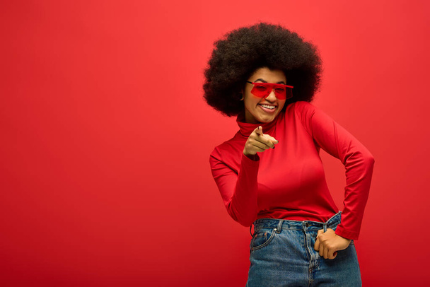 Modna Afroamerykanka pozująca w żywym tle, ubrana w czerwoną koszulę i okulary przeciwsłoneczne. - Zdjęcie, obraz