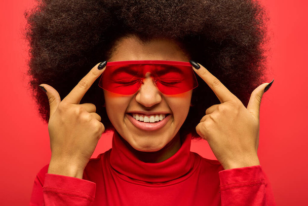 Stílusos afro-amerikai nő piros szemceruzával és bekötött szemmel élénk háttér mellett. - Fotó, kép