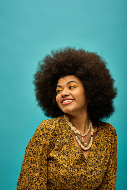 Elegante mujer afroamericana con cabello rizado sonriendo brillantemente para la cámara. - Foto, imagen