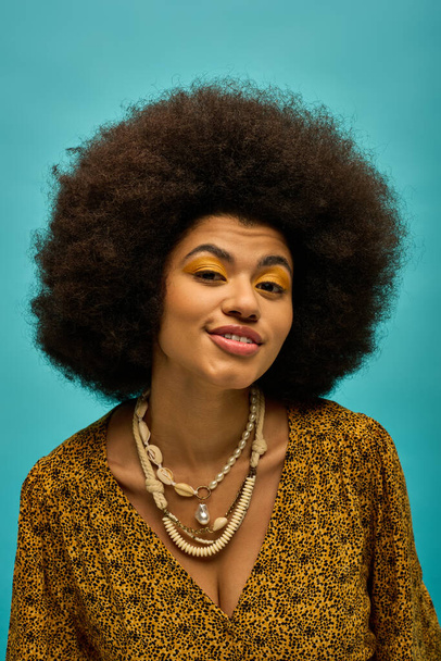 Stylish African american woman showcases trendy attire and necklace on vibrant backdrop. - Photo, Image