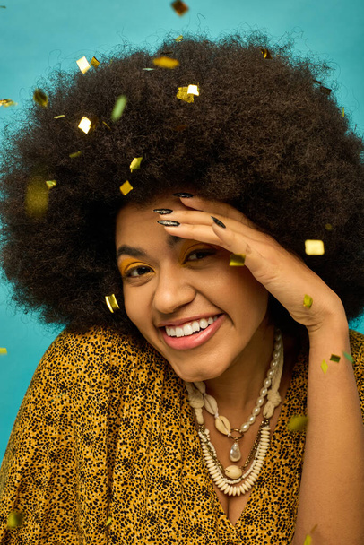 Glimlachende Afro-Amerikaanse vrouw met krullend kapsel omgeven door vallende confetti. - Foto, afbeelding
