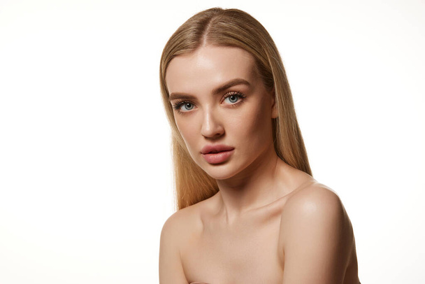Portrait of beautiful young woman with straight blonde air, smooth, clean skin, plump lips and bare shoulders isolated on white background. Concept of natural beauty, cosmetology, cosmetics, skin care - Φωτογραφία, εικόνα