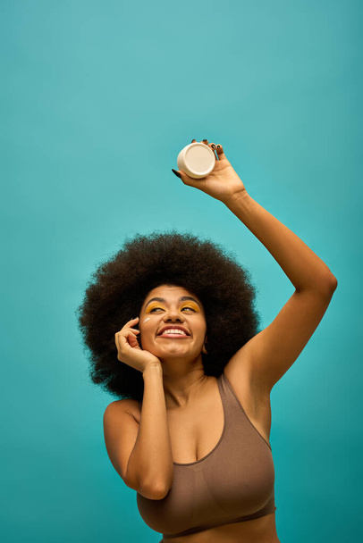 Stylish African American woman holding cream with her iconic afro hairstyle. - Fotografie, Obrázek
