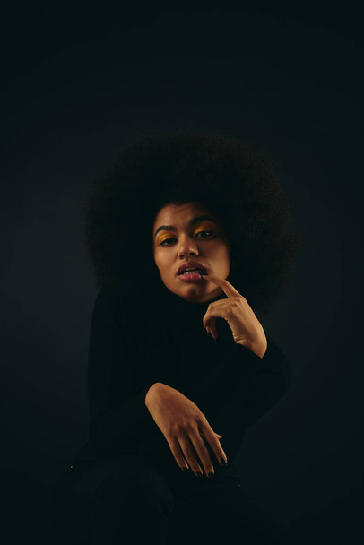 Una mujer afroamericana de moda con el pelo rizado dohairdo posa sobre un telón de fondo vibrante. - Foto, imagen