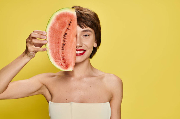 jonge vrouw vreugdevol houdt watermeloen plak in haar gezicht. - Foto, afbeelding