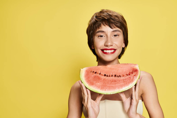 Žena si hravě drží před obličejem plátek melounu. - Fotografie, Obrázek