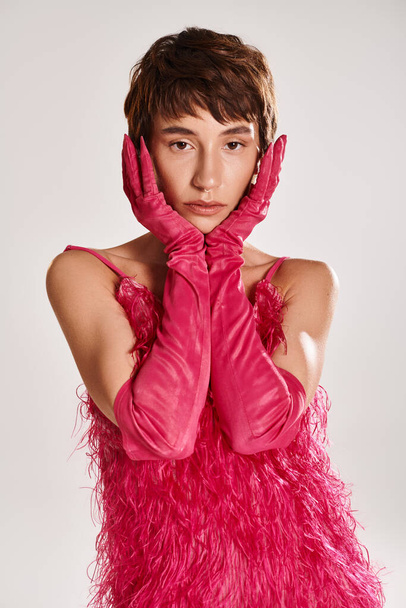 鮮やかな背景にピンクの手袋とピンクのドレスを着ているスタイリッシュな若い女性. - 写真・画像