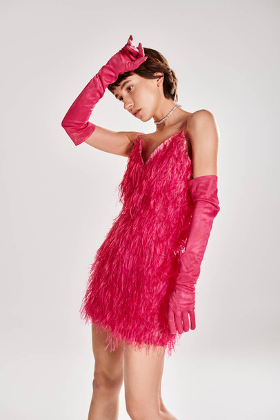 Модная молодая женщина позирует в элегантном розовом платье и перчатках на живом рюкзаке. - Фото, изображение