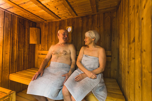 пожилая пара, сидящая в деревянной сауне и прекрасно проводящая время, средне полная, старшая по возрасту концепция. Высокое качество фото - Фото, изображение