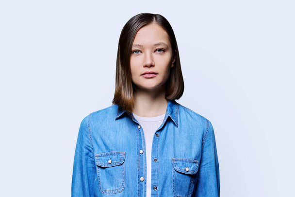 Young beautiful woman on white studio background. Serious attractive 20s female in denim looking at camera. Lifestyle, fashion beauty style, youth concept - Foto, immagini