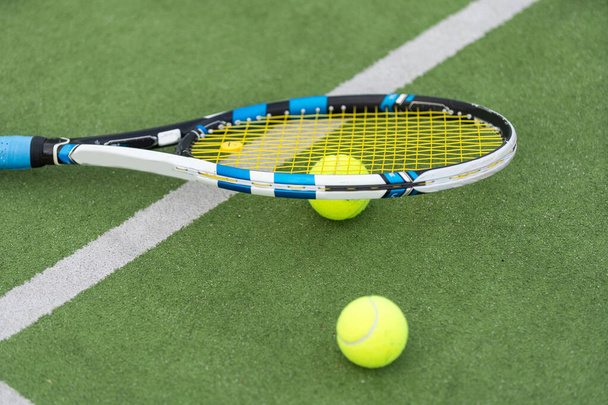 Tennisball und Schläger auf dem Boden des sonnigen Rasen-Tennisplatzes im Freien. Sommer, gesunde Lebensweise, Sport und Hobbys. Hochwertiges Foto - Foto, Bild