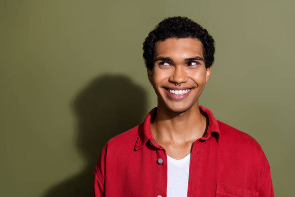Photo of dreamy positive guy wear red shirt smiling white teeth looking empty space isolated khaki color background. - Foto, Bild