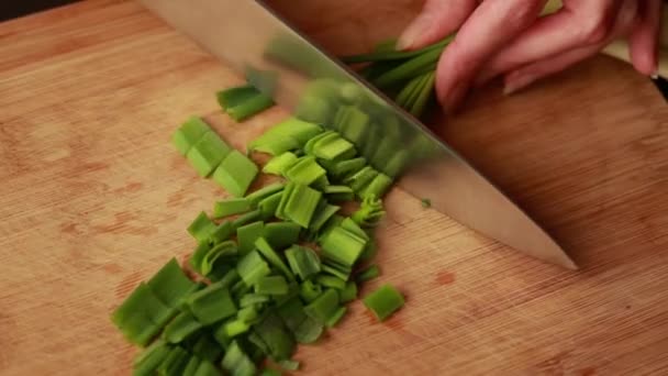 vrouw handen hakken groene ui op houten bord close-up - Video