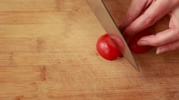 kobieta ręce cięcia pomidorów wiśniowych na drewnianej planszy zbliżenie - Materiał filmowy, wideo