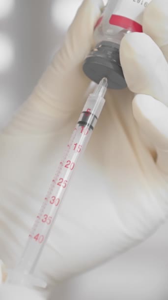 Un esthéticien introduit du Botox dans une seringue pour injection de butuline. Préparation d'une intervention cosmétique dans un salon de beauté par un cosmétologue professionnel gros plan de la main. Des images FullHD de haute qualité - Séquence, vidéo