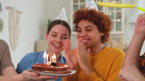 Побажайте. Жінка в вечірній кепці вибухає спалюючи свічки на день народження торта. З днем народження. Група друзів бажає дівчині з днем народження. Люди святкують день народження з вечіркою вдома - Кадри, відео
