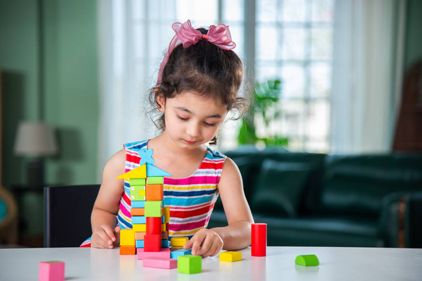Petite fille indienne jouant avec des blocs de bois jouets sur la table à la maison - Photo, image
