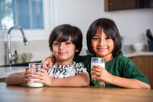 Indiase kinderen die thuis gewone melk drinken of drinken in een glas - Foto, afbeelding