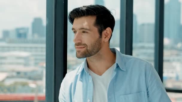 Professional engineer smiling while looking at skyscraper view. Skilled architect in casual outfit looking, planning plan project while standing near panorama window with city scape. Tracery - Footage, Video
