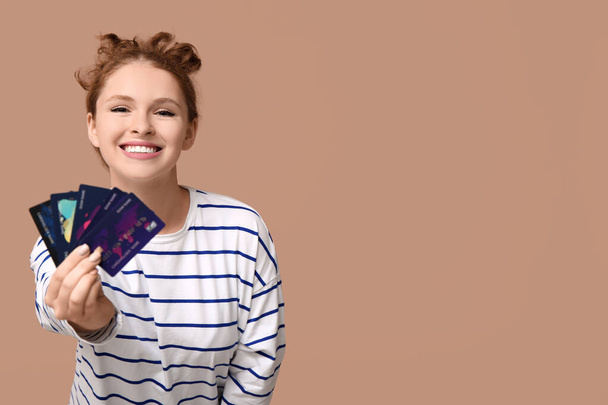 Krásná mladá žena s kreditními kartami na hnědém pozadí - Fotografie, Obrázek