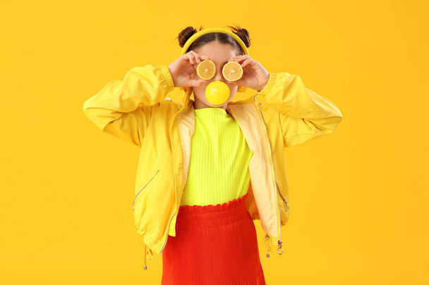 Смішна дівчина з лимонами дме жувальна гумка на жовтому фоні - Фото, зображення