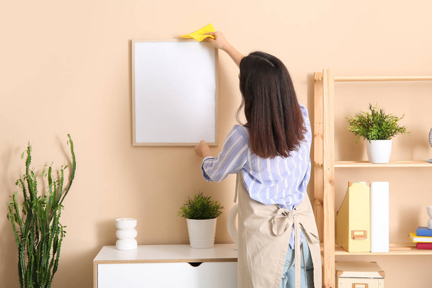 Young woman cleaning furniture in living room - Photo, Image