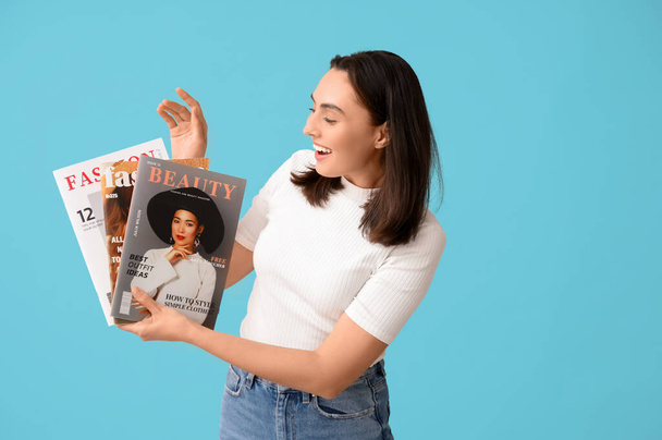 Schöne junge Frau mit Zeitschriften auf blauem Hintergrund - Foto, Bild