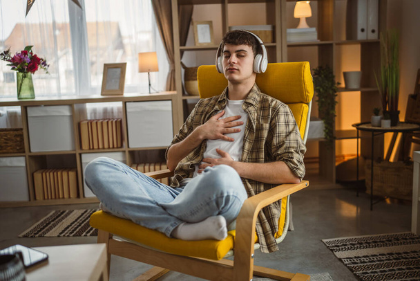 Yksi teini mies tekee opastettu meditaatio jooga itsehoito käytännössä kotona - Valokuva, kuva