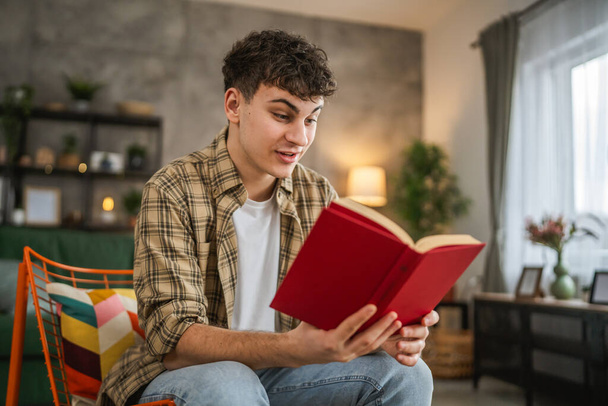 Молодий чоловік кавказький підліток читає книгу вивчення концепції домашньої освіти - Фото, зображення