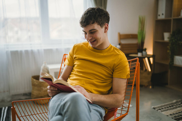 Νεαρός καυκάσιος έφηβος διαβάζει βιβλίο μελέτης στο σπίτι έννοια της εκπαίδευσης - Φωτογραφία, εικόνα