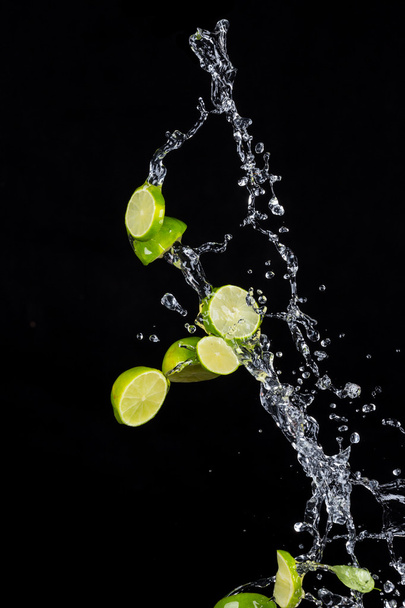 Limes with water splashes on black background - Foto, afbeelding