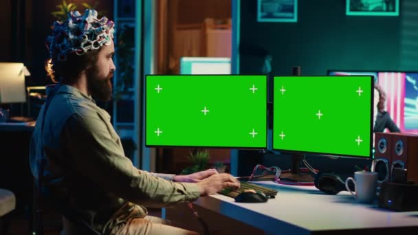 Inżynier komputerowy korzystający z zestawu słuchawkowego EEG, uruchamiający proces przesyłania myśli za pomocą zielonego ekranu PC. Człowiek używający neuronaukowego urządzenia do przenoszenia świadomości w cyberprzestrzeń z monitorami makiety, kamera A - Materiał filmowy, wideo