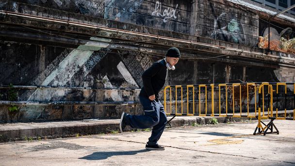 Chiang mai, Thaiföld - Mar 05 2024: Egy hűvös, profi ázsiai férfi hiphop breakdancer divatos ruhákban táncol az utcán, hűvös utcai graffiti a falon. - Fotó, kép
