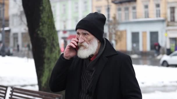 黒い服を着た老人は,冬に外に立って電話で話している. 冬の日に電話で話しているおじいちゃん - 映像、動画