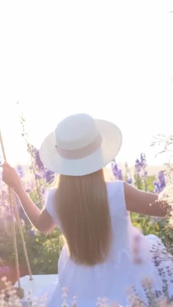 Una mujer con un vestido y sombrero blanco captura felizmente una selfie, con un hermoso paisaje como telón de fondo. Evento divertido, pulgares de viaje hacia el cielo y la hierba - Metraje, vídeo
