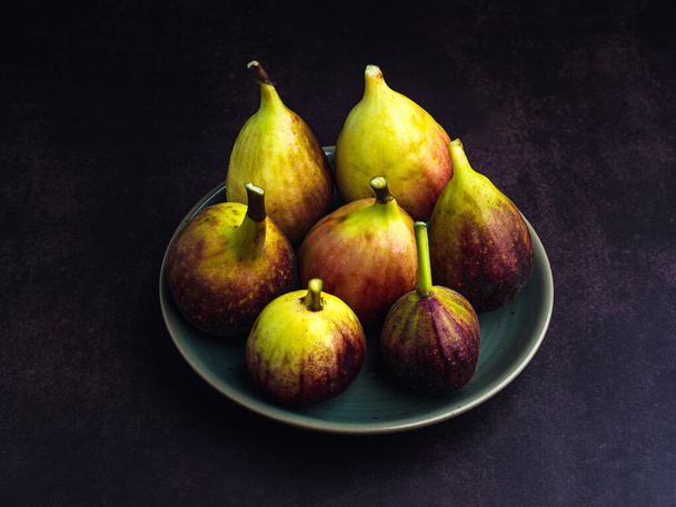 Fruta de figos maduros está em um prato com um fundo vintage. Fruta rica em vitaminas. Fotografia de perto. Frutos saudáveis e conceito de saúde. - Foto, Imagem