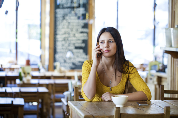  Beautiful brunette girl sitting in a coffee shop - Foto, imagen