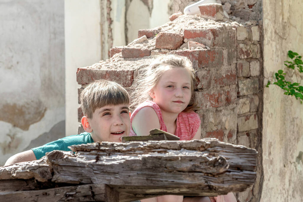 軍事と軍事の紛争のゾーンで放棄され、破壊された建物の子供たち。ホームレスの子どもたちの社会問題の概念ステージングされた写真. - 写真・画像