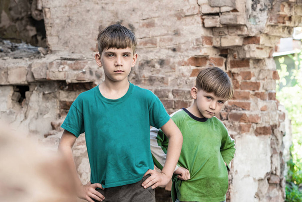 Deux frères tristes et malheureux dans un bâtiment détruit et abandonné, mise en scène photo. - Photo, image