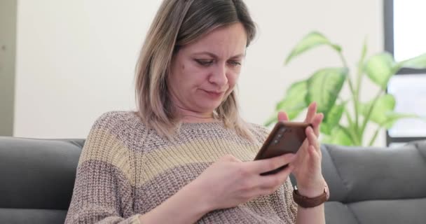 Mulher insatisfeita lendo notícias on-line usando telefone celular filme 4k câmera lenta. Comunicação remota através do conceito de redes sociais - Filmagem, Vídeo