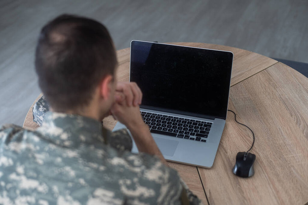 Young hispanic man army soldier using laptop sitting on table at home. High quality photo - Photo, Image