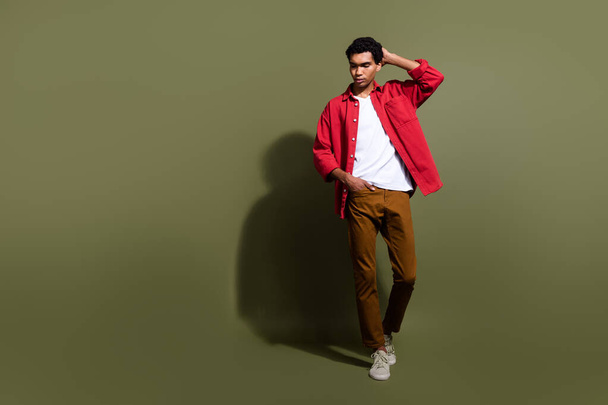 Full length photo of cool handsome man dressed red shirt walking looking empty space isolated green color background. - 写真・画像