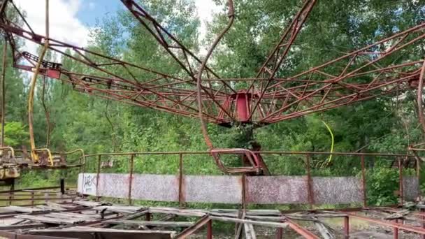 Eerie scène van een verlaten pretpark: een roestige draaimolen ingehaald door de natuur. - Video