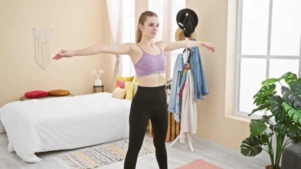 Una joven mujer caucásica practica yoga en su dormitorio luminoso y acogedor, retratando la salud y la calma. - Imágenes, Vídeo